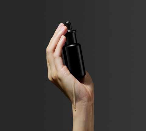 Hand holding bottle of organic face oil